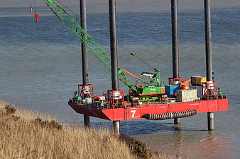 Red offshore construction barge with crane in water