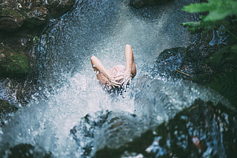 Woman splashing in a natural waterfall stream