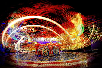 Long exposure light trails on a spinning fairground ride at night