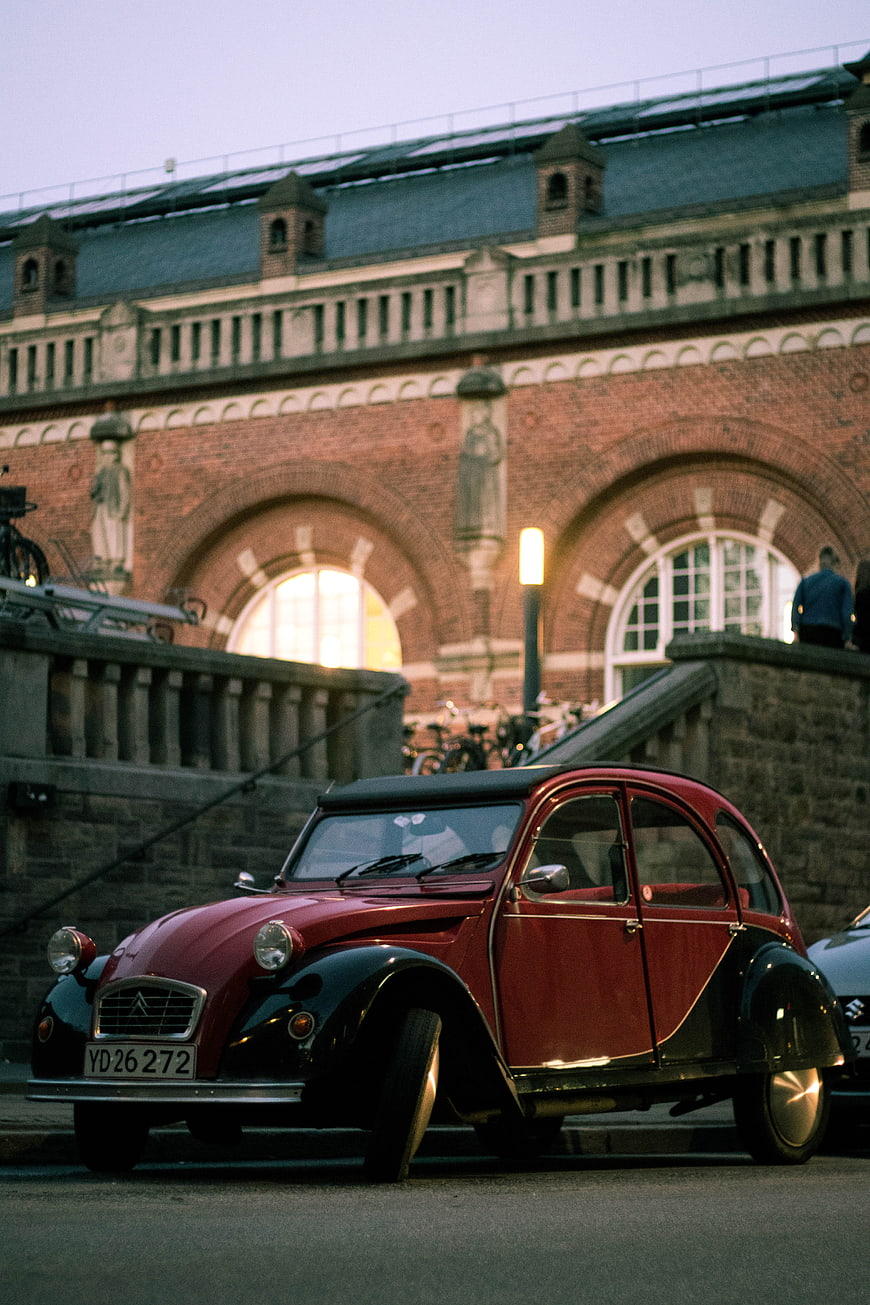 Vintage Red Citroën 2CV Parked in Front of Brick Architecture
