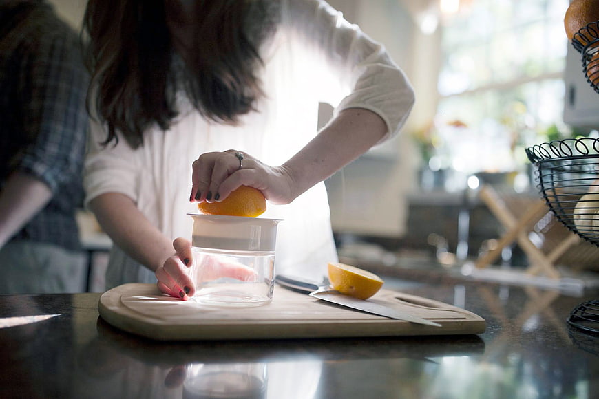 Woman Squeezing Fresh Orange Juice in Kitchen
