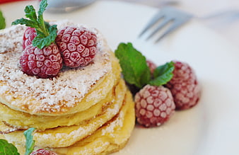 Stack of fluffy pancakes topped with fresh raspberries and mint