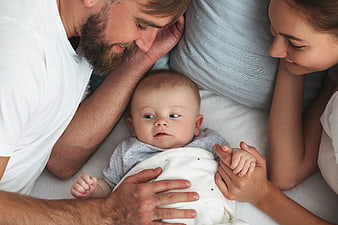 Top View of Parents Lying in Bed with Newborn Baby