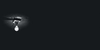 Single light bulb hanging in dark room with copyspace