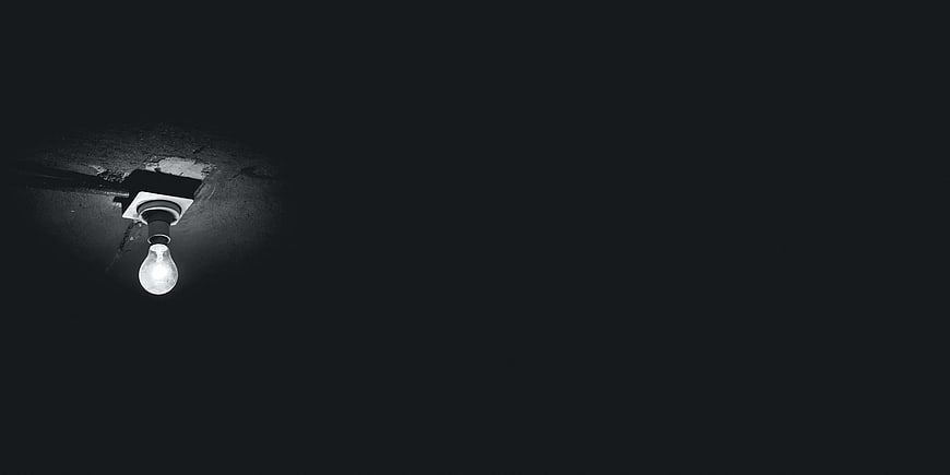 Single light bulb hanging in dark room with copyspace