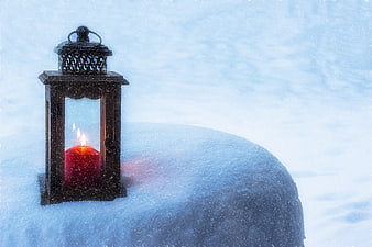 Lantern with red candle in snow