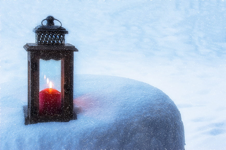 Lantern with red candle in snow