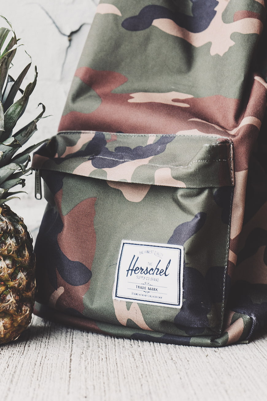 Camouflage Herschel Backpack with Pineapple on Wooden Surface