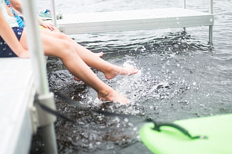 Children splashing feet in lake water from dock