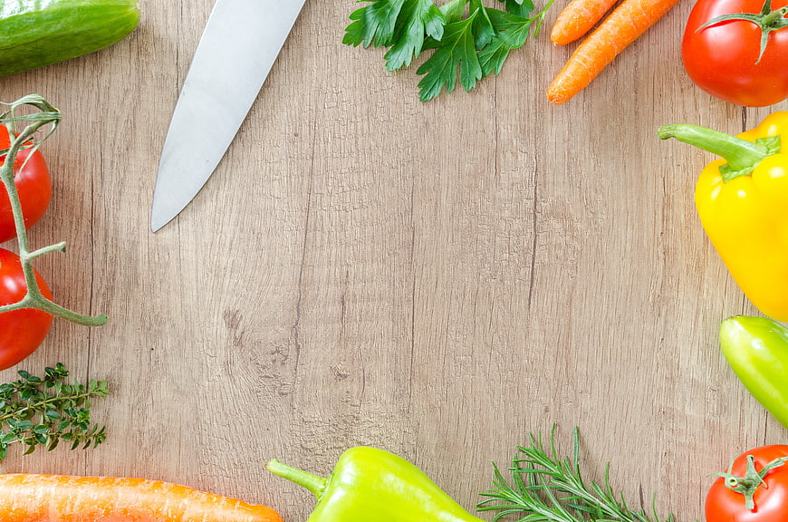 Fresh vegetables and herbs on wooden cutting board with knife