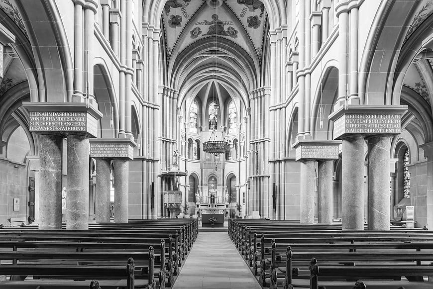 Black and white interior of Gothic church with pews and altar