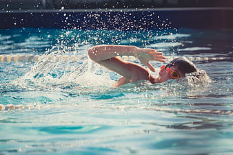Young swimmer performing freestyle stroke in outdoor pool