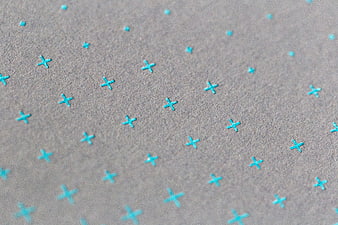 Close-up of textured gray paper with cyan cross pattern