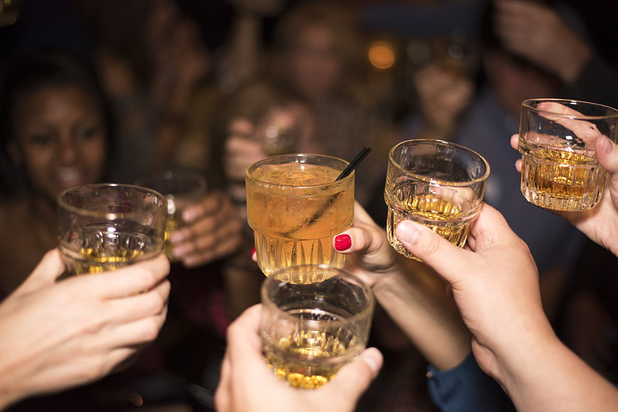 Friends clinking whiskey glasses in a toast at a party