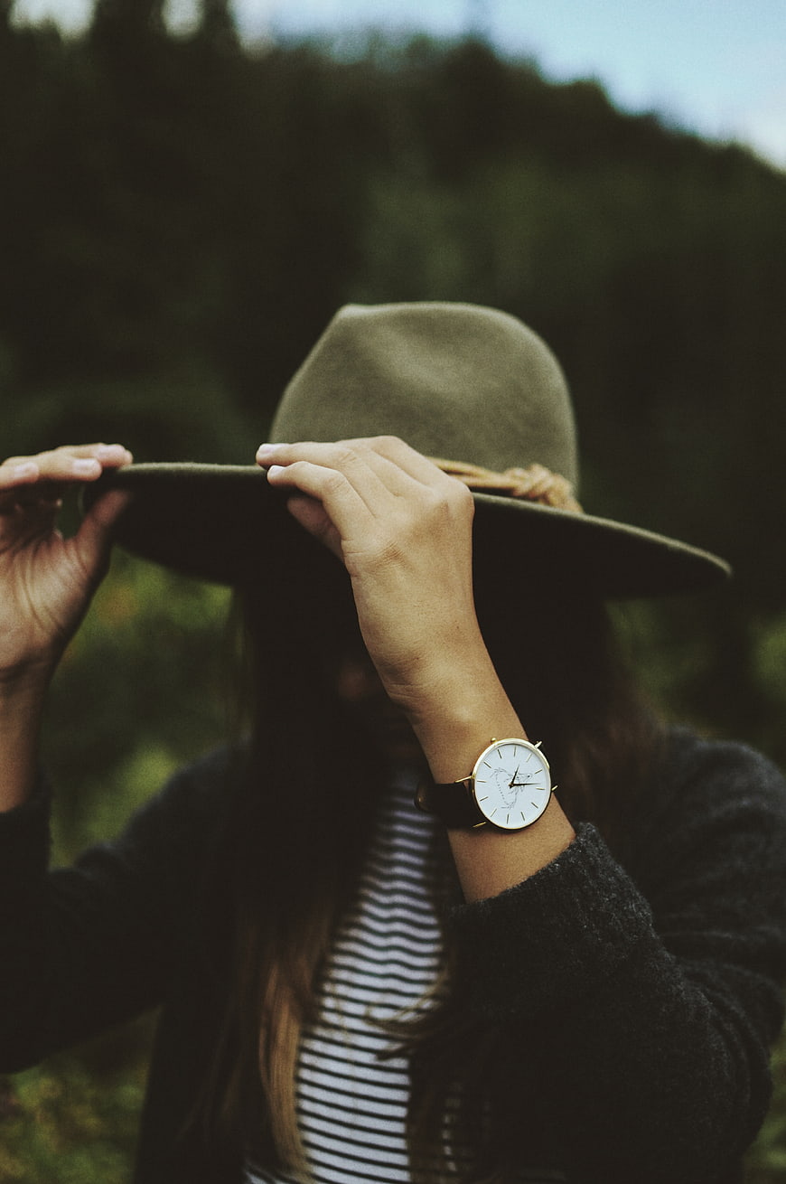 Woman holding hat with wristwatch in nature
