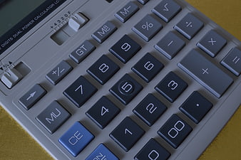 Close-up of a grey and blue desk calculator keypad on a gold surface