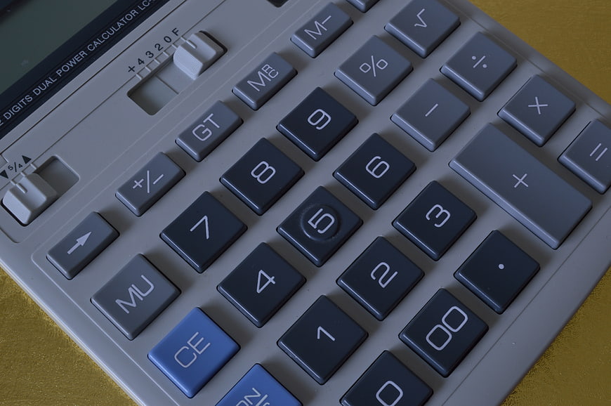 Close-up of a grey and blue desk calculator keypad on a gold surface