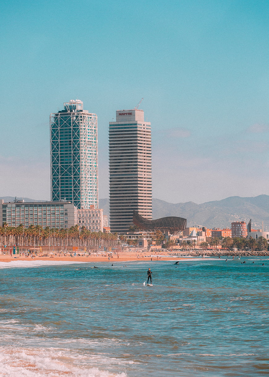 Surfer on paddleboard with Barcelona skyline and beach