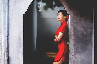 Woman in Red Cheongsam Standing in Arched Doorway