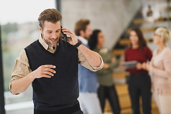 Happy businessman talking on phone in modern office