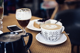 Cappuccino with latte art and cake on wooden table