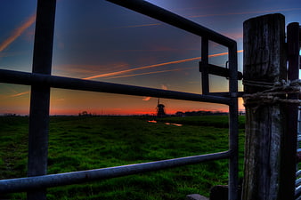 Dutch windmill silhouette at sunset through metal gate
