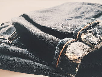 Close-up of folded blue denim jeans with orange stitching