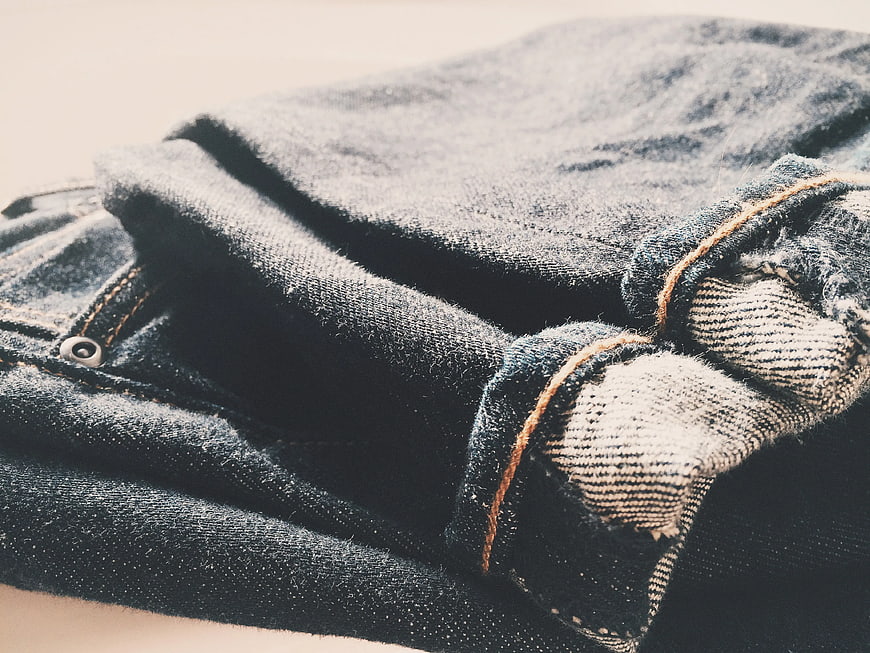 Close-up of folded blue denim jeans with orange stitching