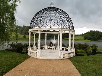 Elegant white gazebo with black dome by a lake for wedding ceremony