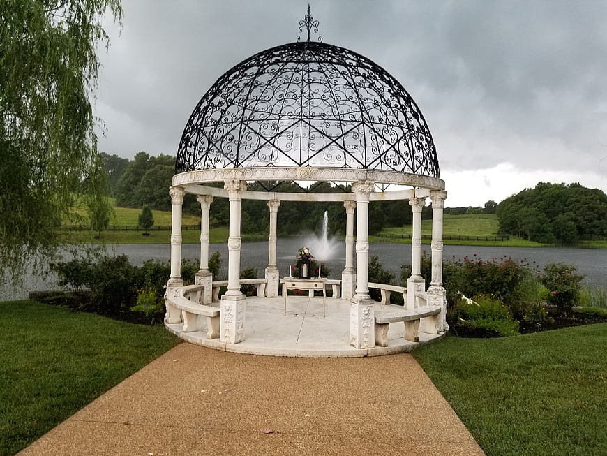 Elegant white gazebo with black dome by a lake for wedding ceremony