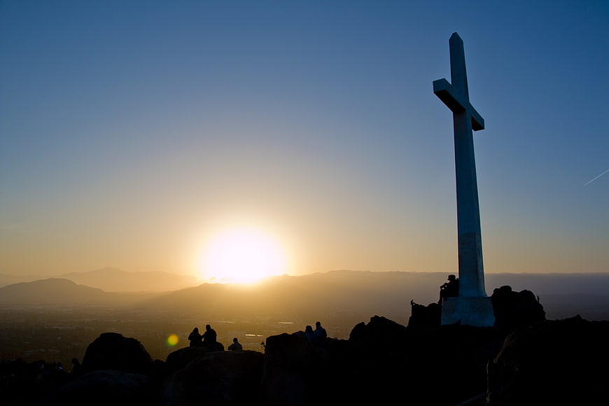 Silhouette of a Blue Cross on a Mountain at Sunrise