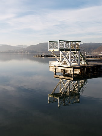 White diving platform on calm lake with reflection