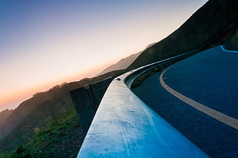 Winding Mountain Road at Sunset with Guardrail