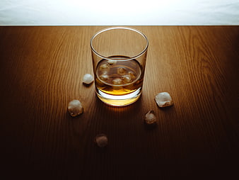 Glass of Whiskey on the Rocks with Ice Cubes on Wood