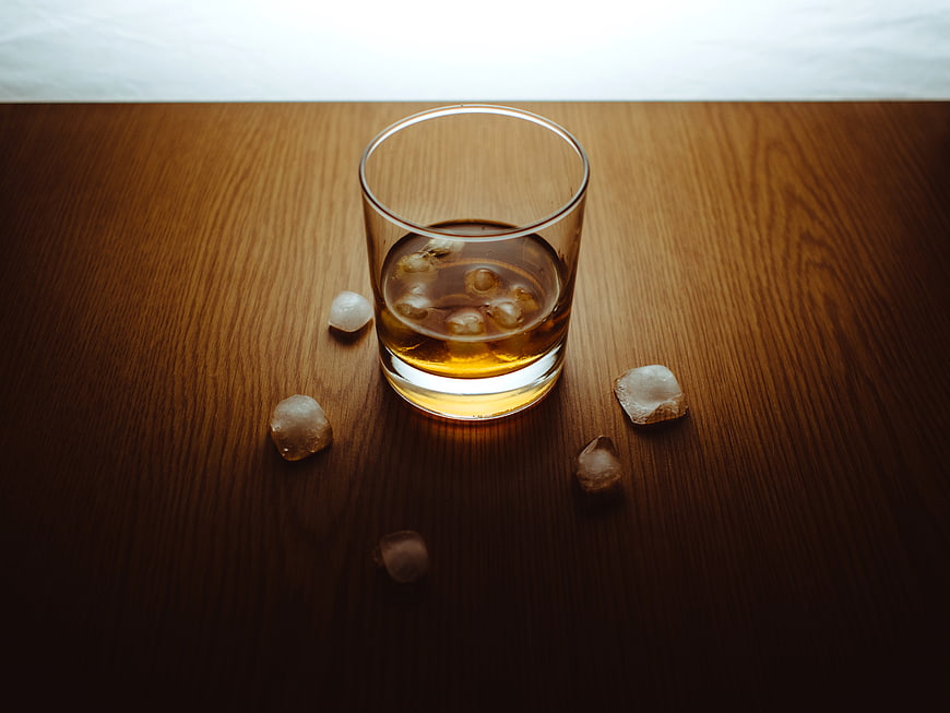 Glass of Whiskey on the Rocks with Ice Cubes on Wood