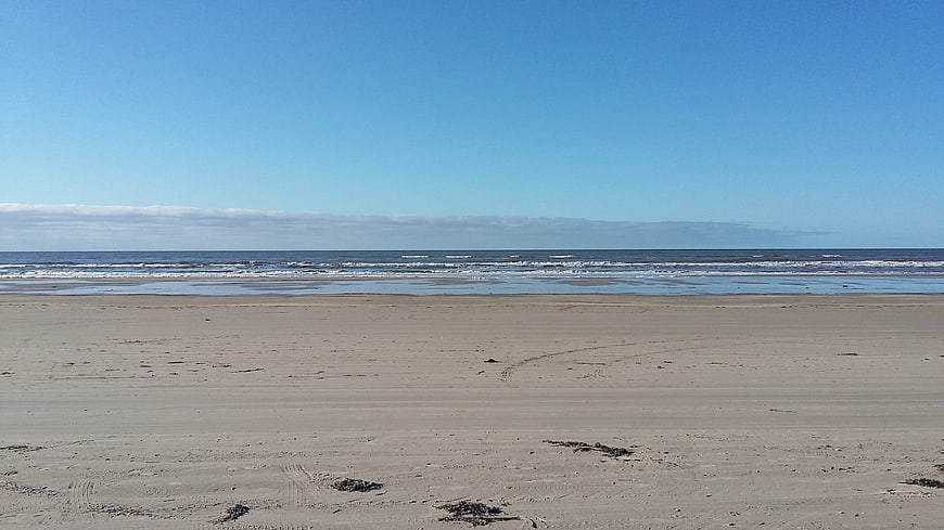 Wide sandy beach with blue sky and ocean waves