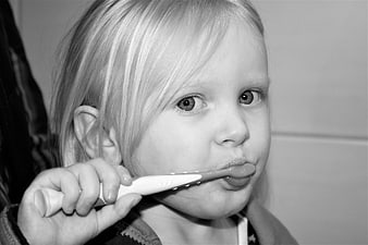 Cute toddler brushing teeth with toothbrush in black and white