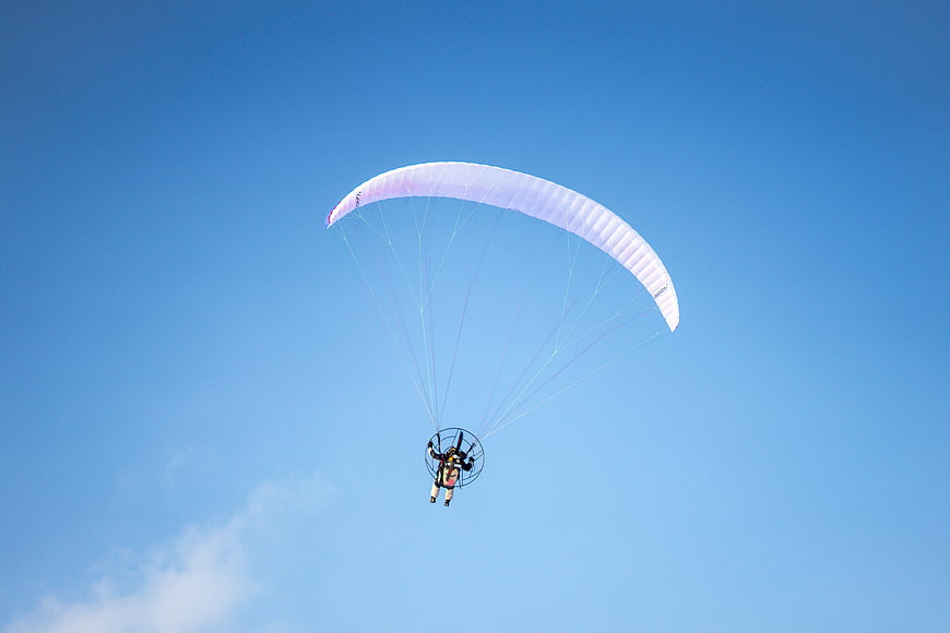 Paramotor flying high in clear blue sky