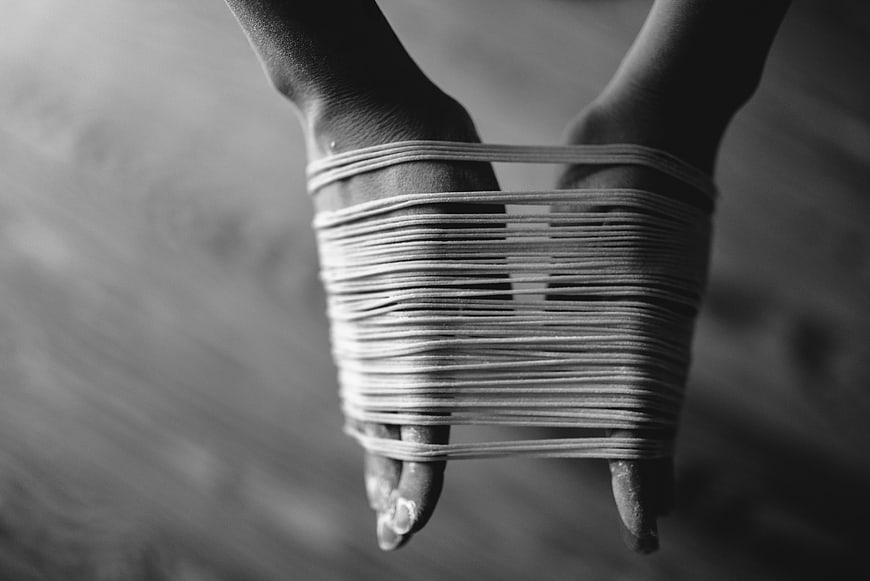 Black and white photo of hands bound by rubber bands