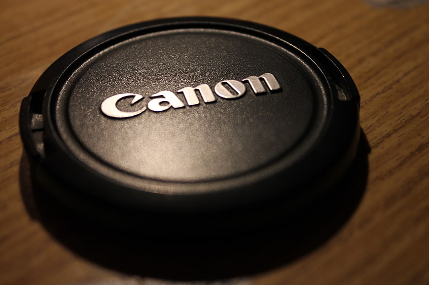 Close-up of Canon lens cap on wooden surface