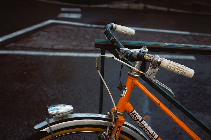 Close-up of vintage orange bicycle handlebars on wet street