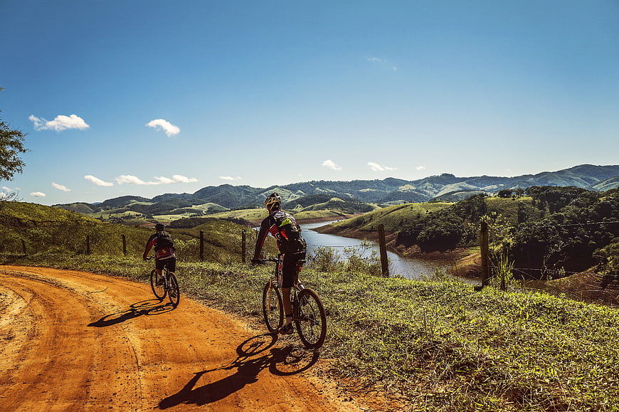 Mountain bikers on dirt road overlooking river valley