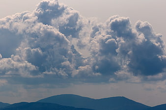 Dramatic cumulus clouds over blue mountain silhouette