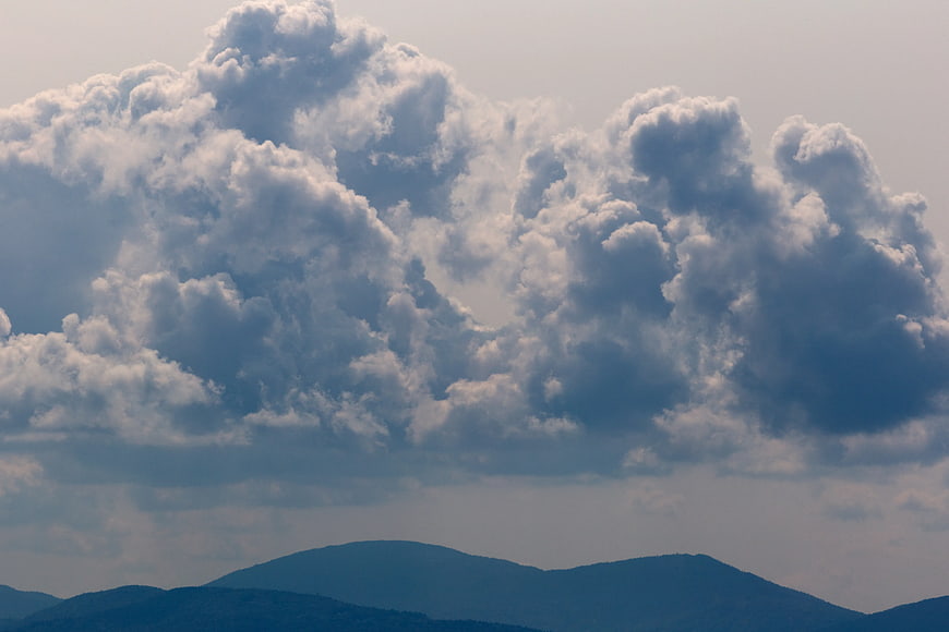Dramatic cumulus clouds over blue mountain silhouette