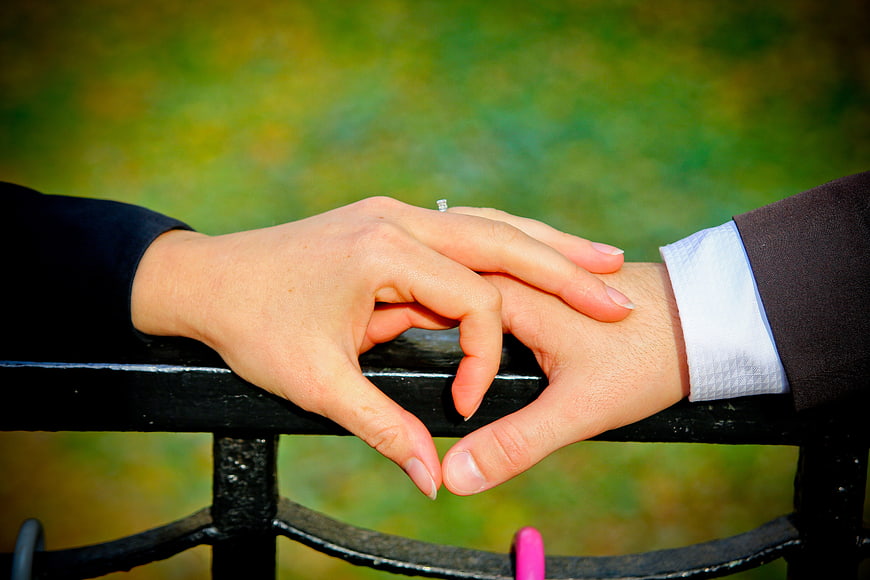 Couple forming heart shape with hands on park bench