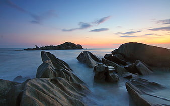 Serene Sunset Seascape with Smooth Misty Water and Granite Rocks