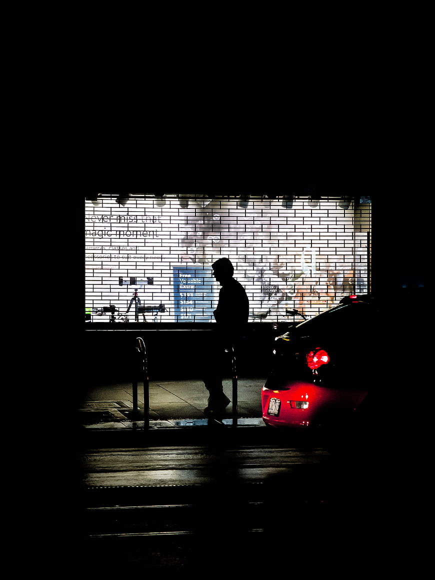 Silhouette of person waiting by car at night