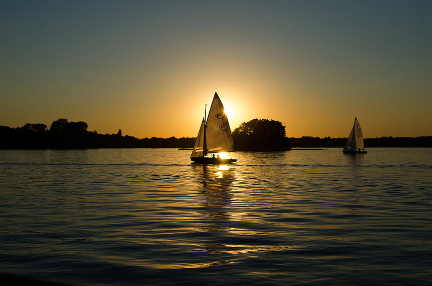 Sailboats Silhouetted Against Golden Sunset on Calm Water