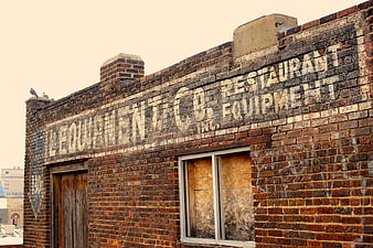 Vintage Ghost Sign on Weathered Brick Building Wall