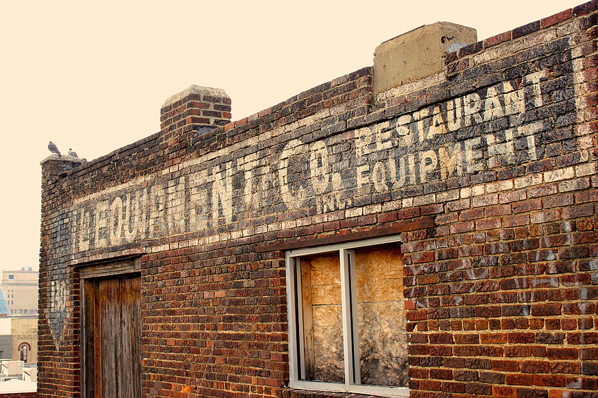 Vintage Ghost Sign on Weathered Brick Building Wall